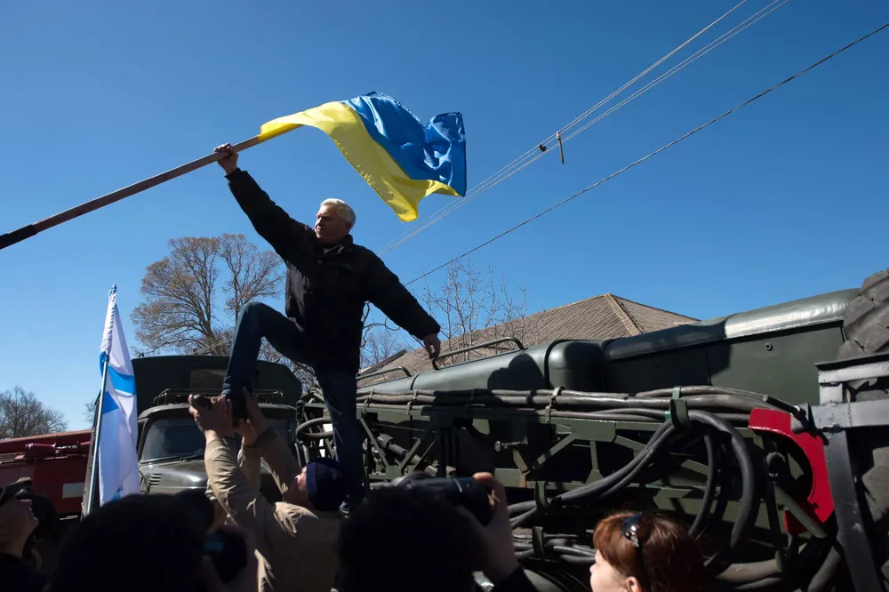 Manifestantes pro rusos bajan una bandera ucraniana en la base aérea de Novofedorivkax.