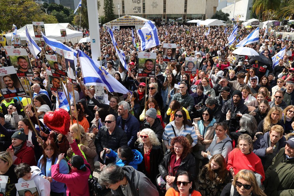 La gente observa la liberación de los rehenes israelíes Avera Mengistu y Tal Shoham en una pantalla grande en la Plaza de los Rehenes en Tel Aviv.