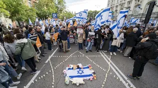 Una bandera y velas en el suelo durante una manifestación por la liberación de los rehenes secuestrados por Hamás, frente al Congreso de los Diputados en España.