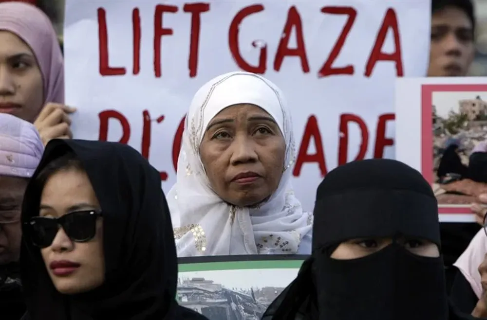 Manifestantes filipinos sujetan pancartas y encienden velas durante una protesta contra los ataques del ejército israelí