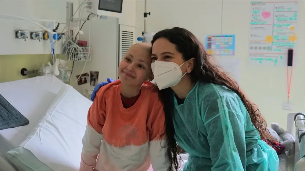 La cantante Rosalía junto a Gala, paciente pediátrica con cáncer, en una planta de hospitalización del Pediatric Cancer Center Barcelona del Hospital Sant Joan de Déu.